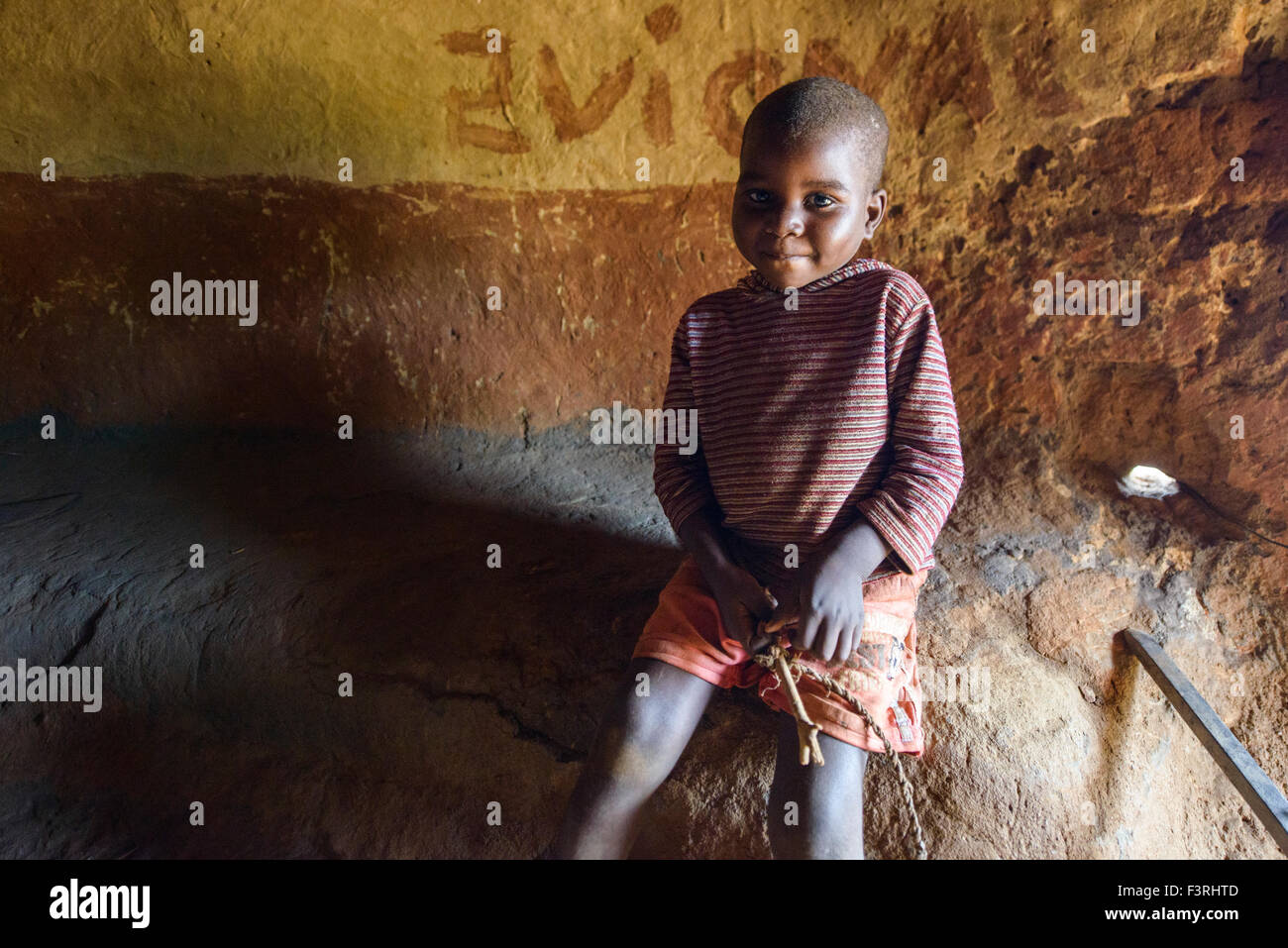 Boy sitting in traditional straw hut, Mozambique, Africa Stock Photo