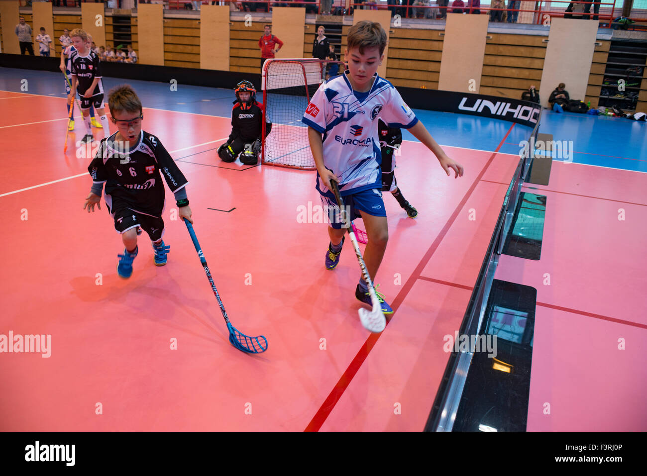Children boys schoolchildren playing floorball (floor hockey) match in