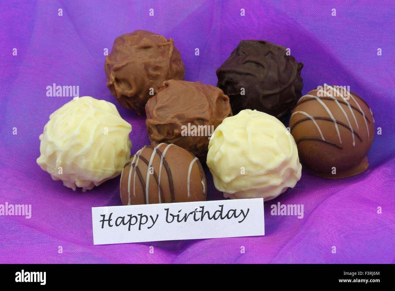 Happy birthday card with assorted chocolates, truffles and pralines on purple background Stock Photo