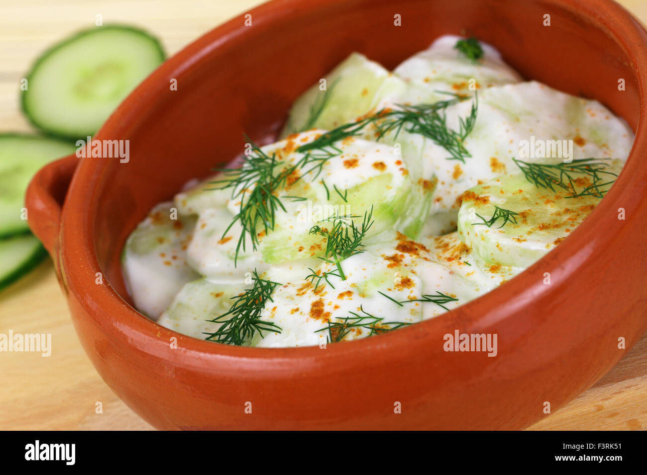 Cucumber in sour cream with  paprika and fresh dill in traditional clay bowl Stock Photo
