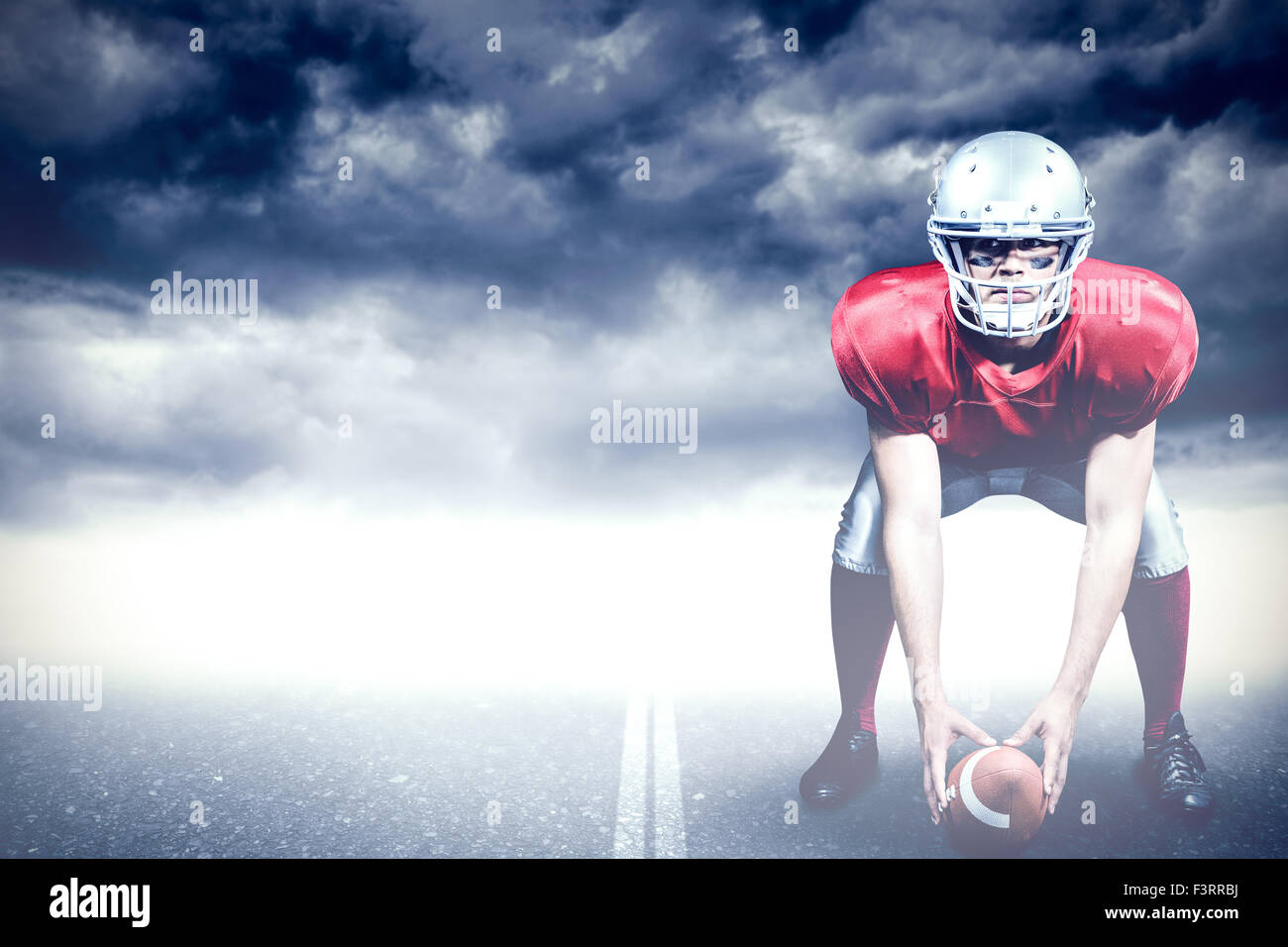 Composite image of american football player bending while holding ball Stock Photo