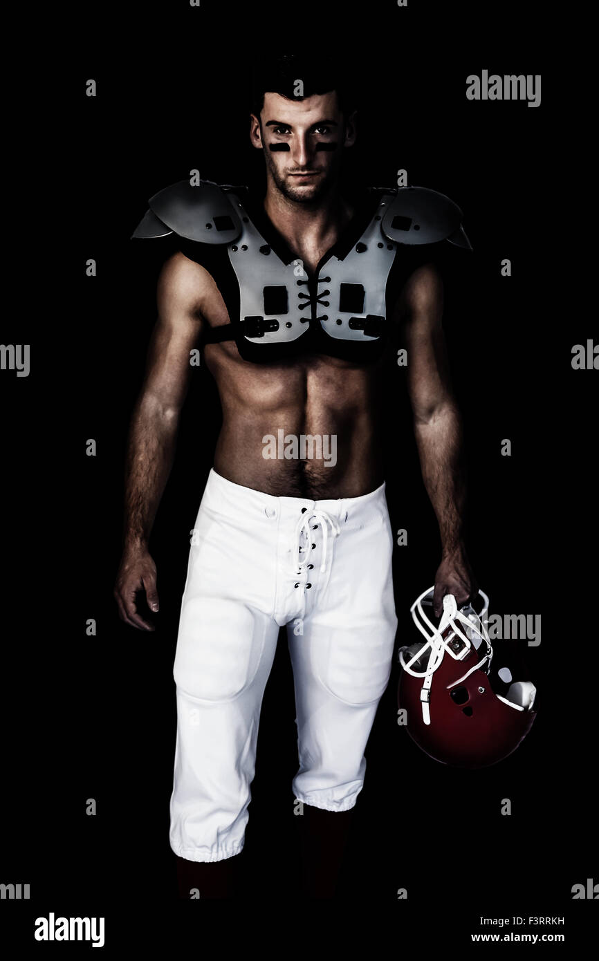 Composite image of portrait of rugby player wearing shoulder pads and holding helmet Stock Photo
