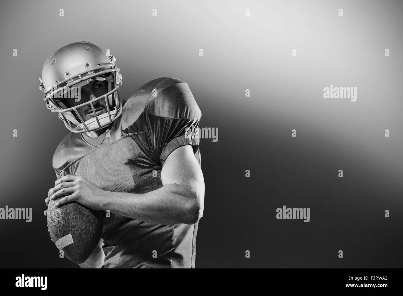 American football player in red jersey looking away while holding ball Stock Photo