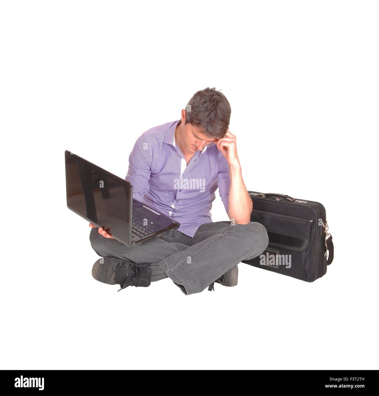 A man sitting on the floor holding his laptop thinking about the ...