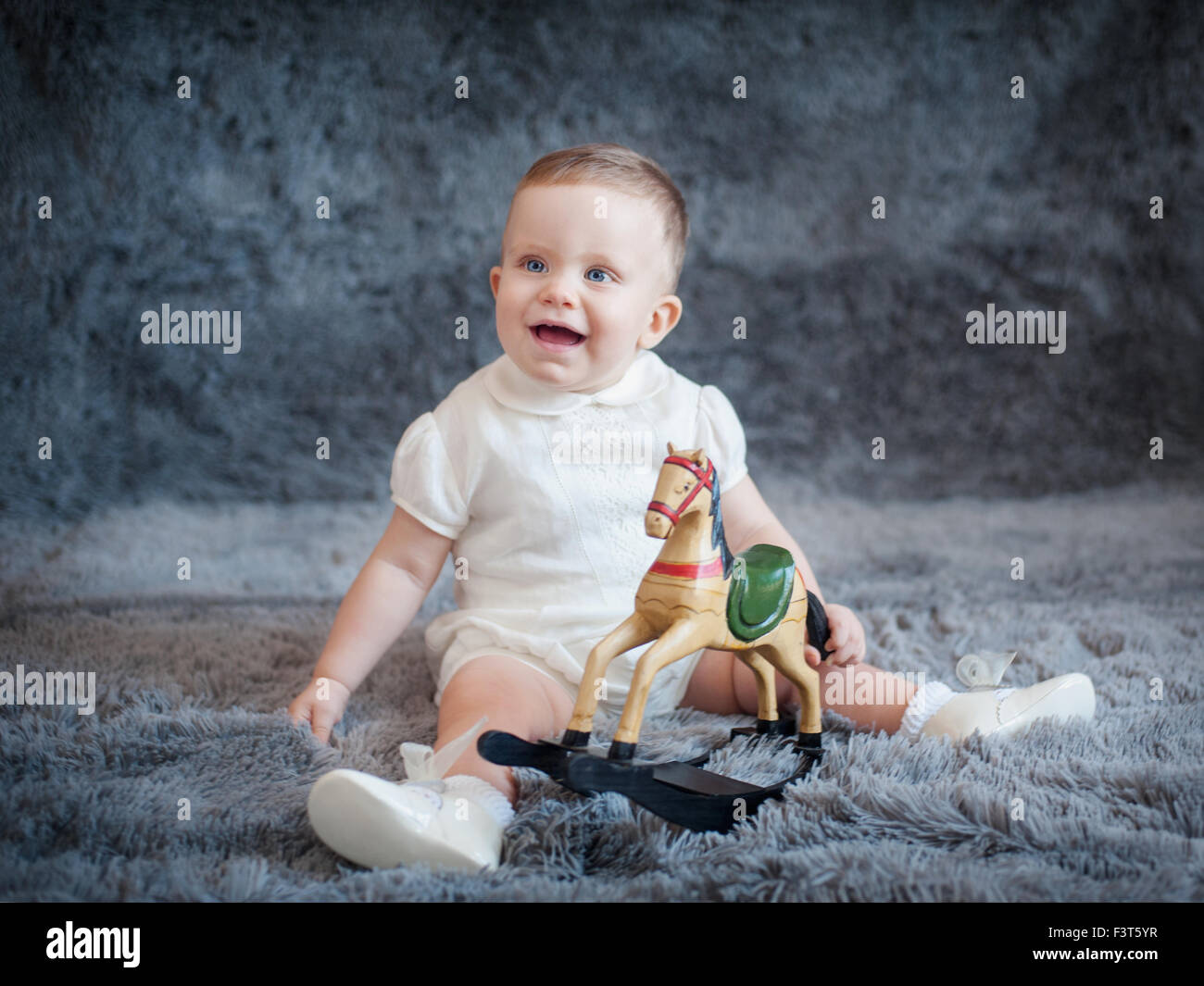Cute boy on a gray background with a toy horse in his hands Stock Photo