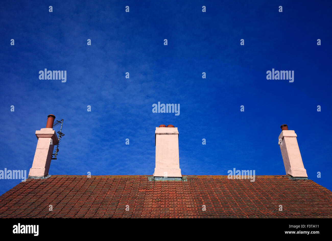 Bright pink painted houses and chimneys against a blue sky. Stock Photo