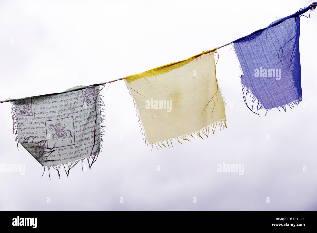Traditional Buddhist prayer flags flying against an overcast grey sky Stock Photo