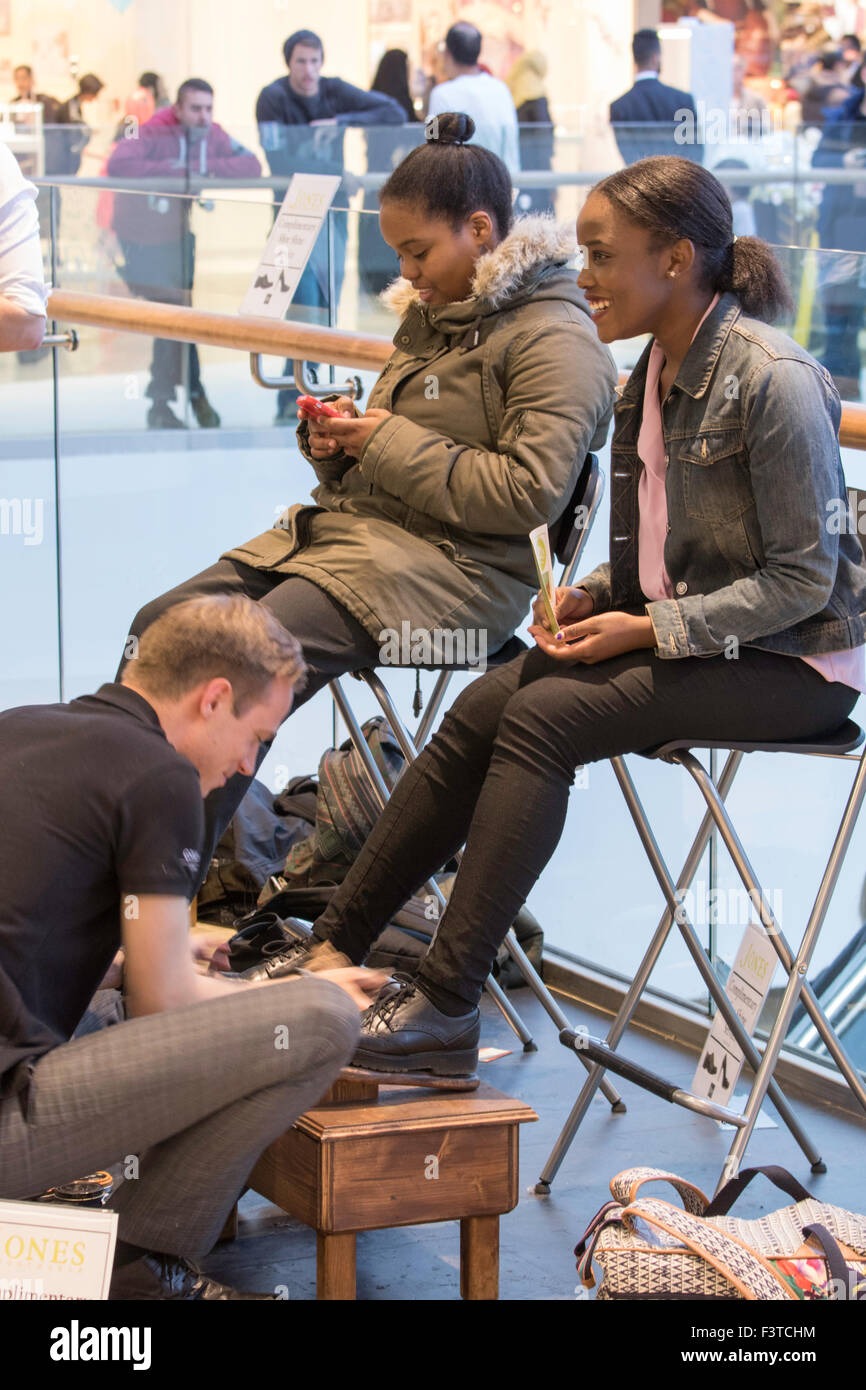 Two teenagers having their shoes polished at Birmingham Grand Central shopping centre, Birmingham, England, UK Stock Photo
