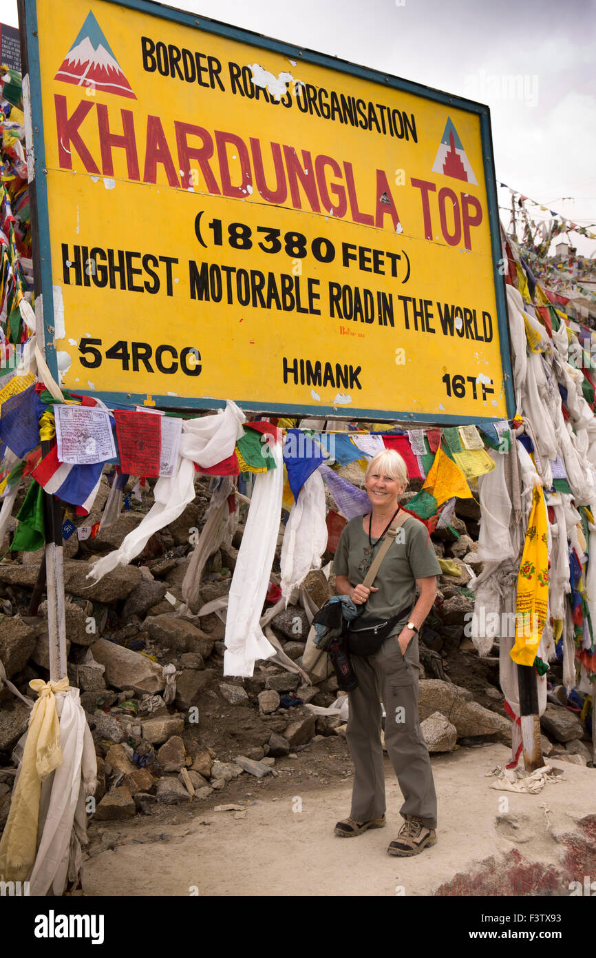 India, Jammu & Kashmir, Ladakh, Leh, Khardung La Pass top, female tourist and prayer flags at summit sign Stock Photo