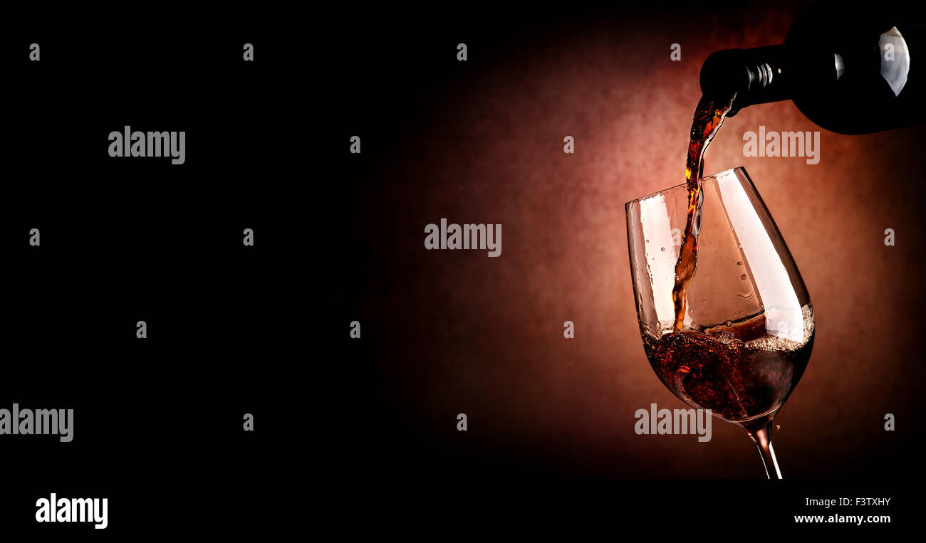 Wine pouring in wineglass on the brown background Stock Photo