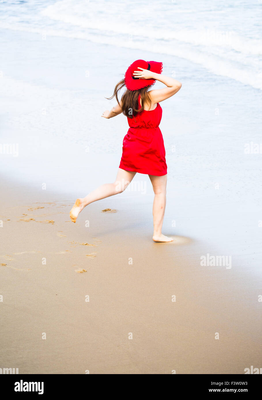 Young woman in a red dress on the beach Stock Photo
