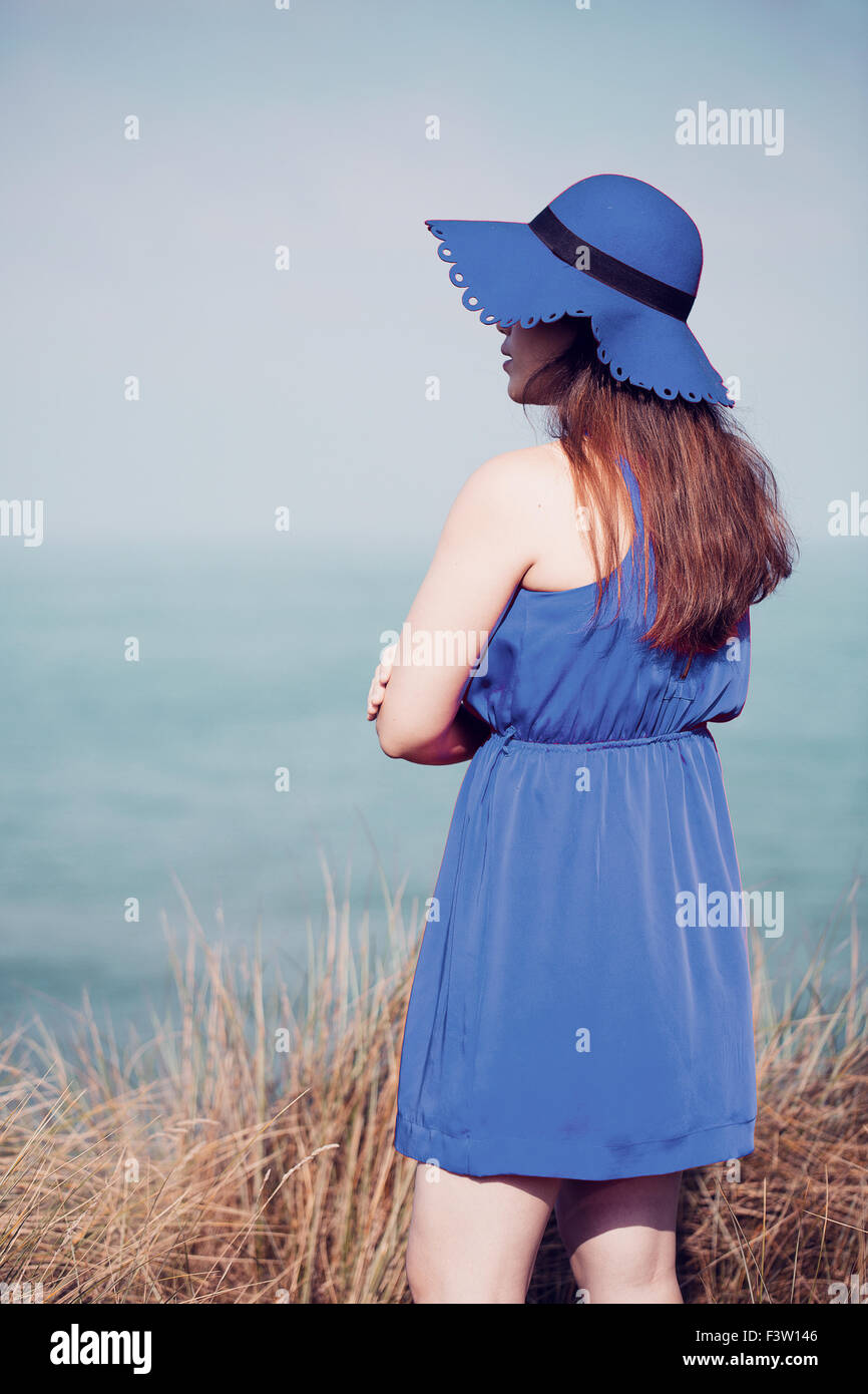 Young woman wearing a blue hat and dress at the beach Stock Photo