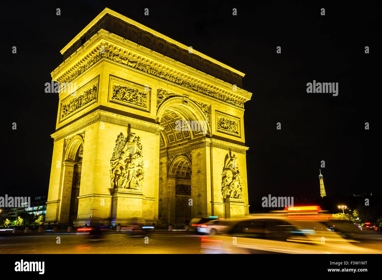 A taxi flashes by the Arc de Triomphe on a summer night, the Eiffel Tower stands in the background. Paris, France. August, 2015. Stock Photo