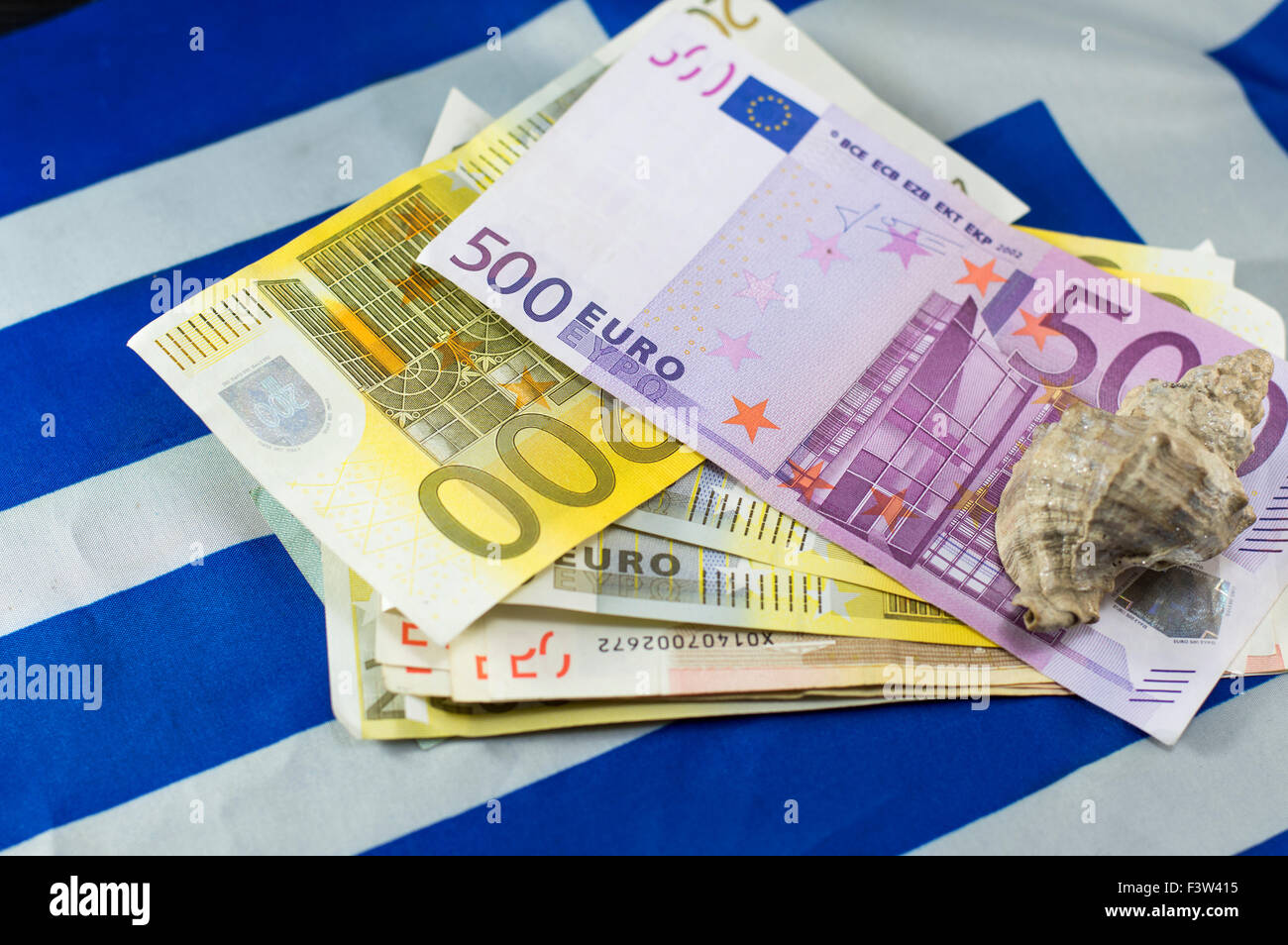 Euro bills on the Greek flag and the shell on top, with low depth of field. Tourism income abstract Stock Photo