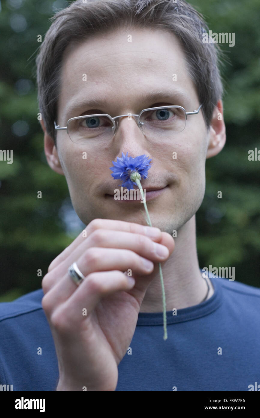 A man smelling a cornflower Stock Photo