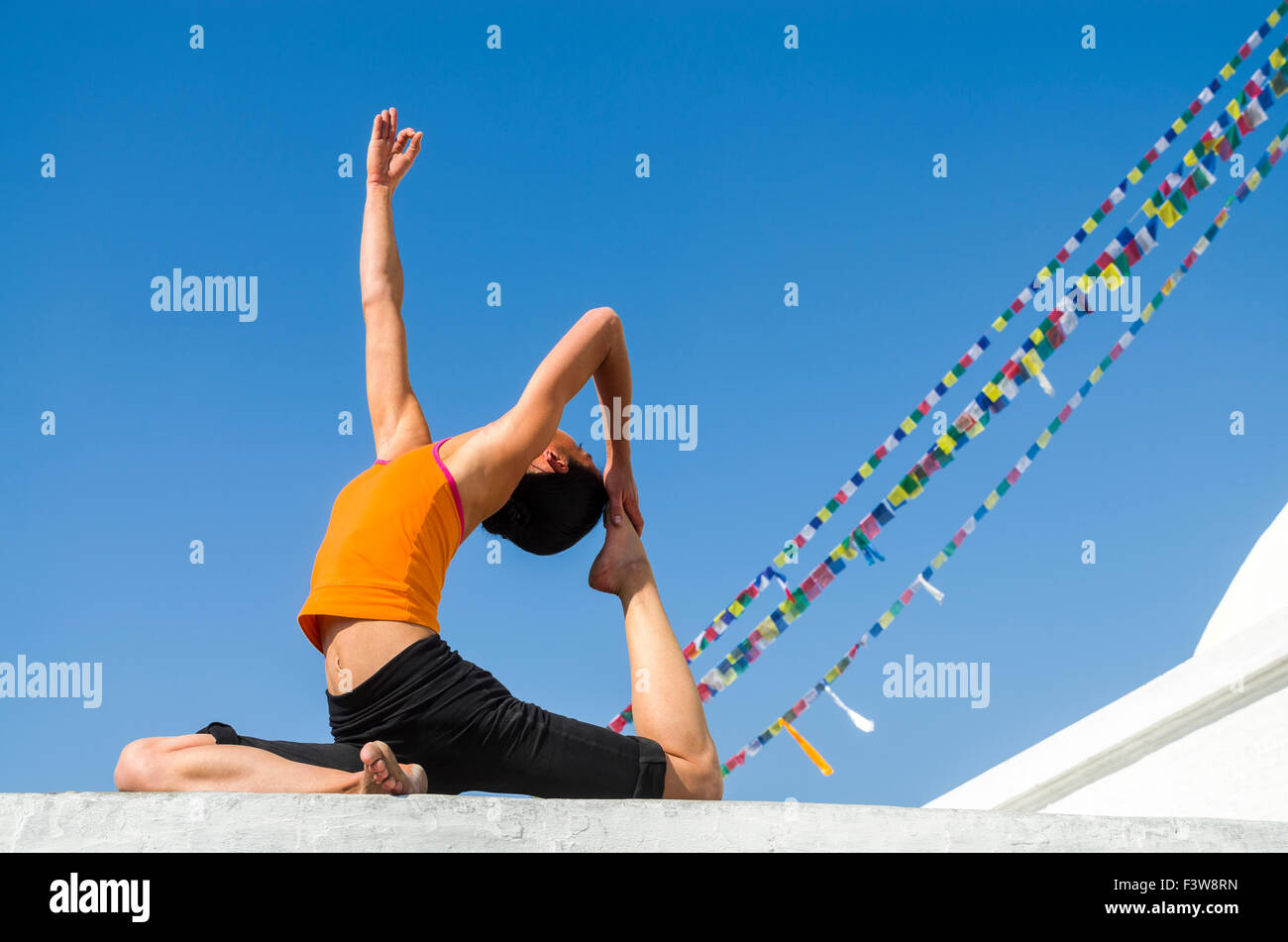 Young woman practicing yoga at Boudnath Stupa, showing the pose