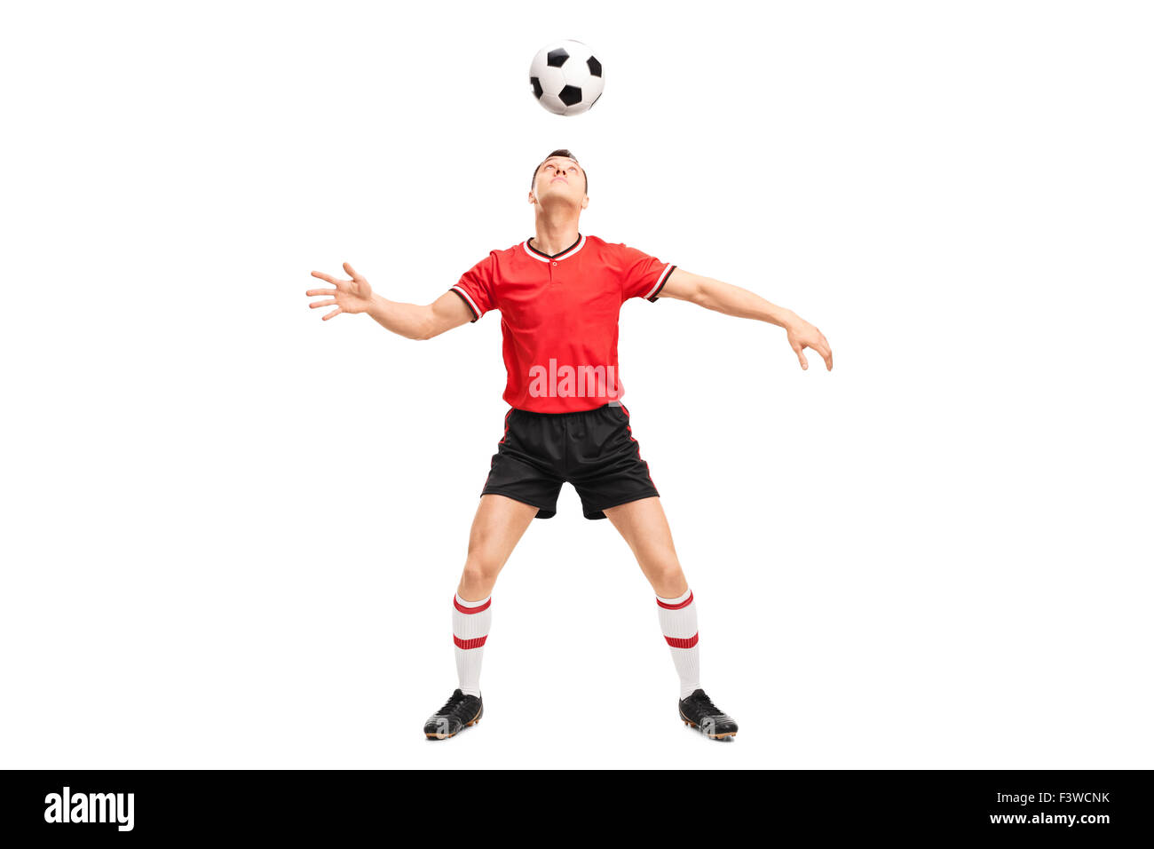 Full length portrait of a young male football player juggling a ball on his head isolated on white background Stock Photo