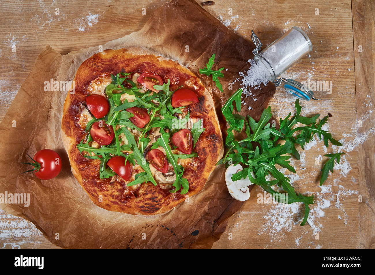 Delicious, juicy and tasty rustic homemade vegetarian pizza on wooden board with cherry tomato, rucola, mozzarella and basil Stock Photo