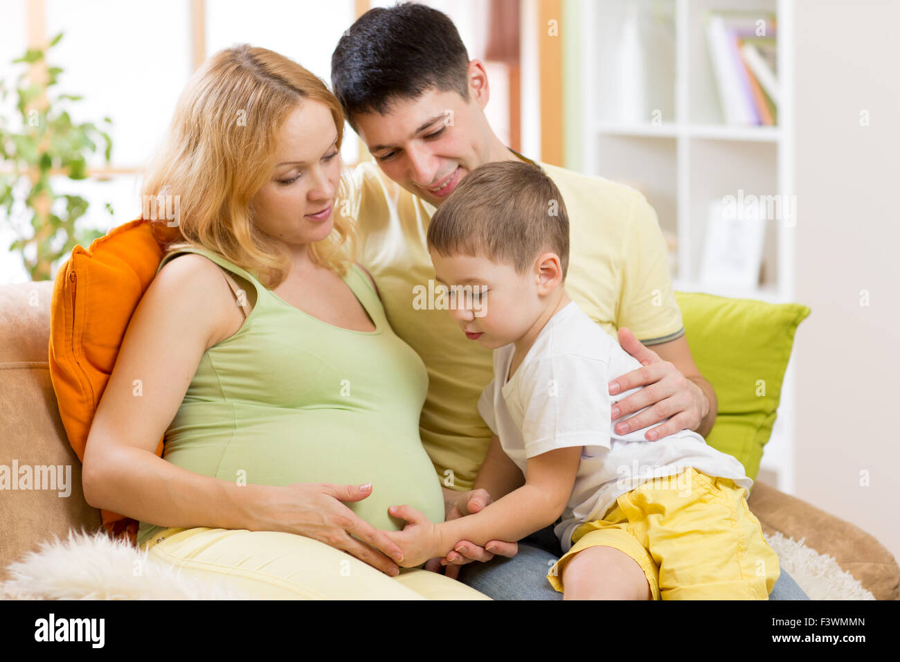 Family expecting new baby.  Little boy touching pregnant mother belly Stock Photo