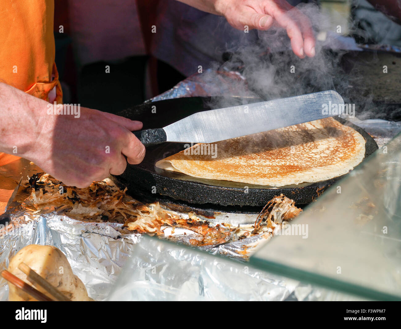 Person making a pancake on a hot plate at a food festival in Bakewell