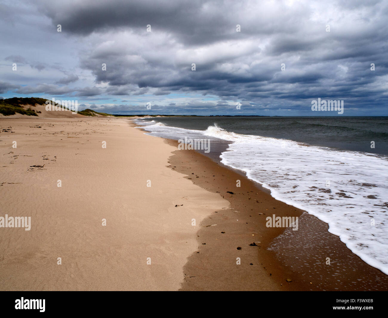 Sand Dunes and Tide under Dark Clouds at Druridge Bay near