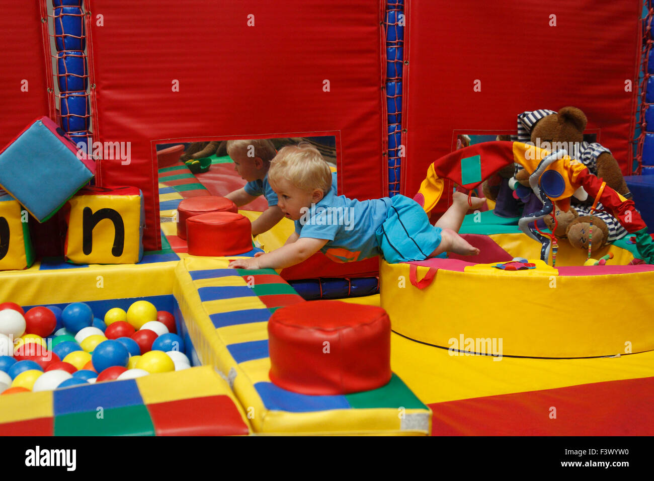 Toddler learning to negotiate objects in relative safety in a play barn Stock Photo