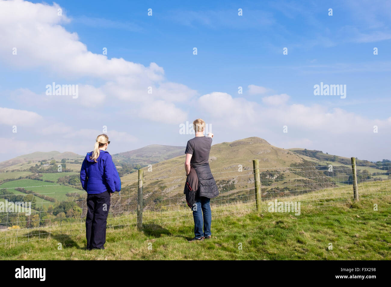 Millennial couple looking at a view to Roundton fort from Todleth Hill, Churchstoke or Church Stoke (Yr Ystog) Montgomery Powys Mid Wales UK Britain Stock Photo