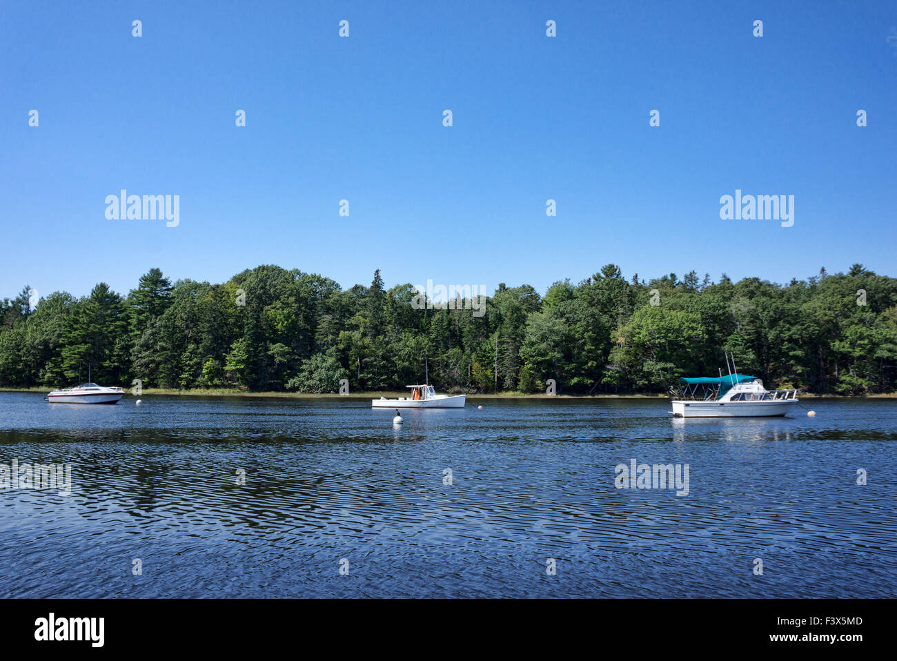 Three boats moored on Union River at Ellsworth Maine in the summertime