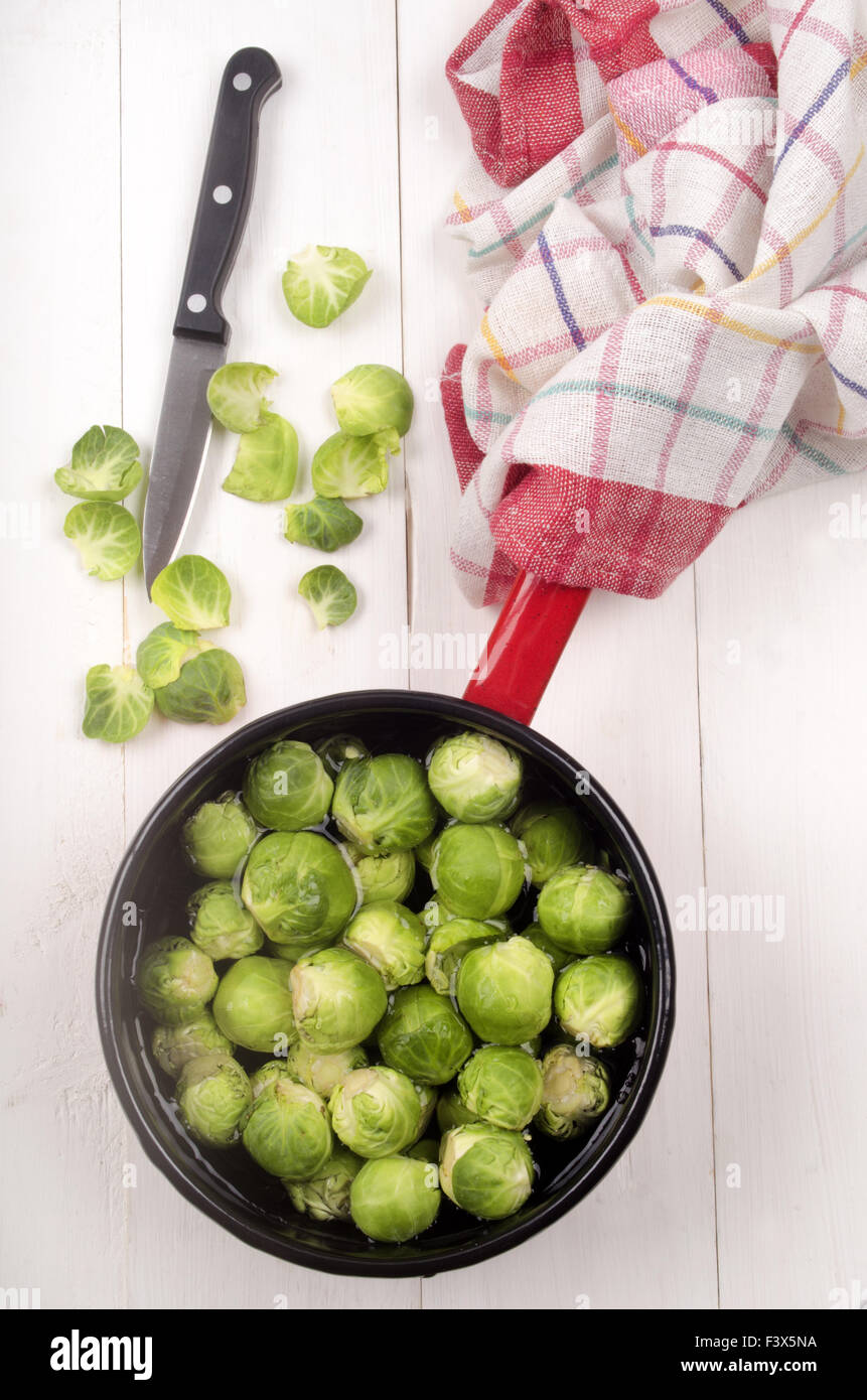brussels sprouts with water in a pot, kitchen knife and tea towel Stock Photo