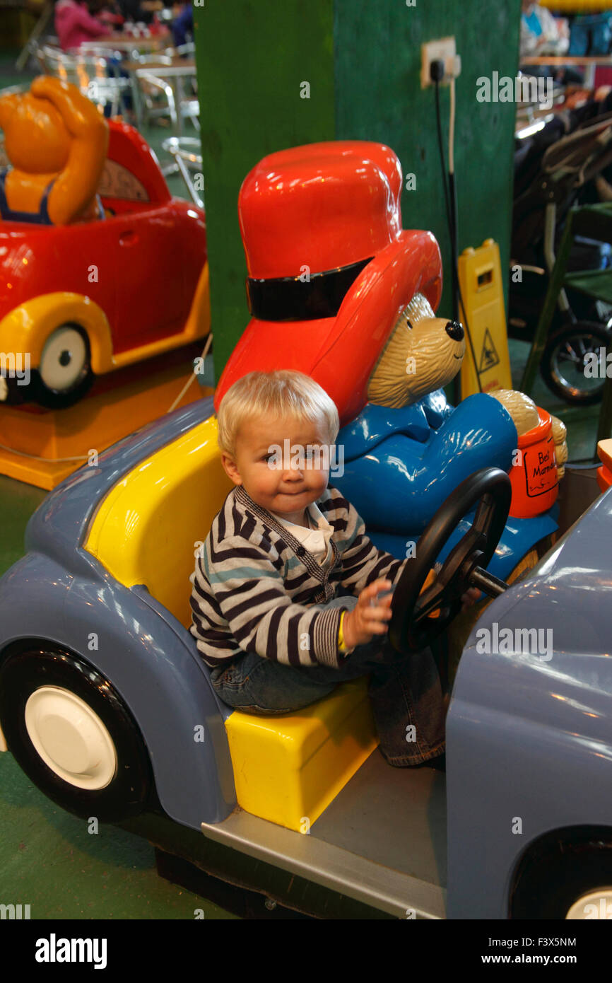 Toddler riding on fairground merry go round in paddington car Stock Photo