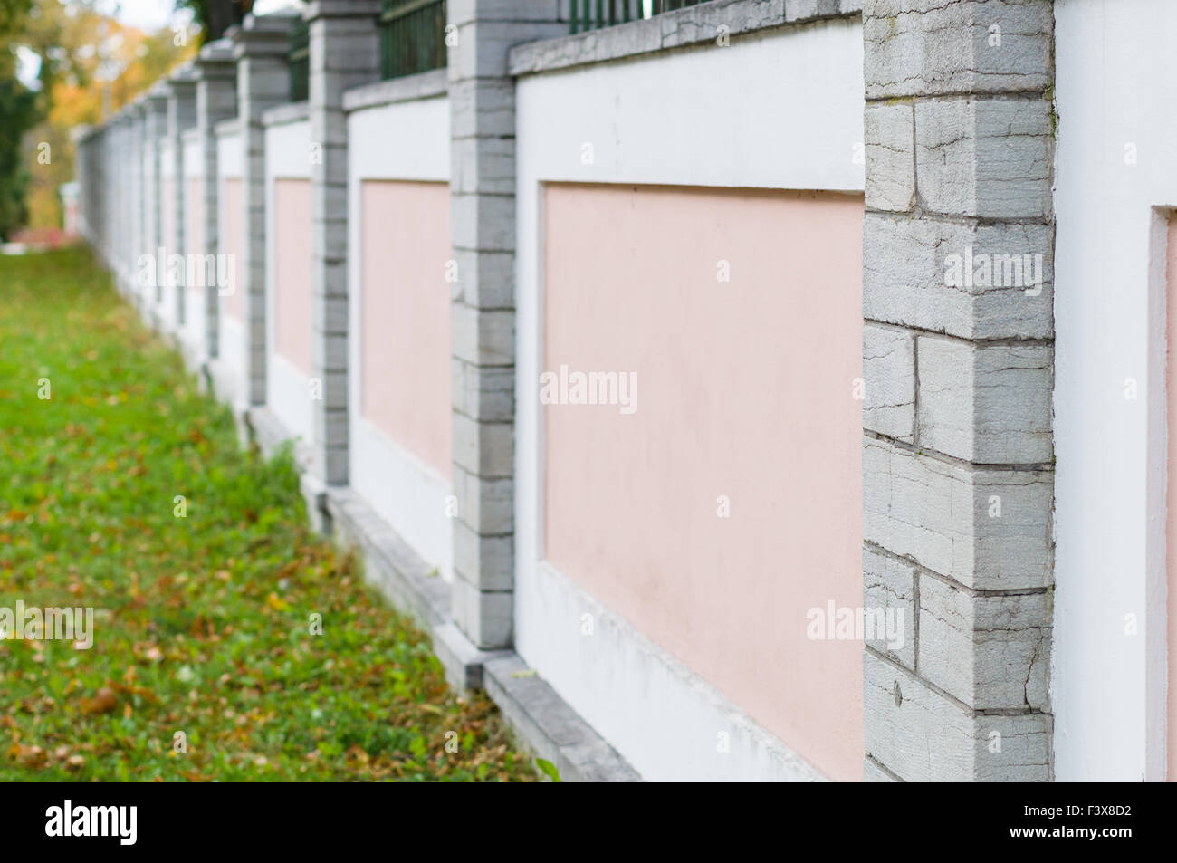 Pink and white concrete fence with stone columns, diminishing perspective Stock Photo