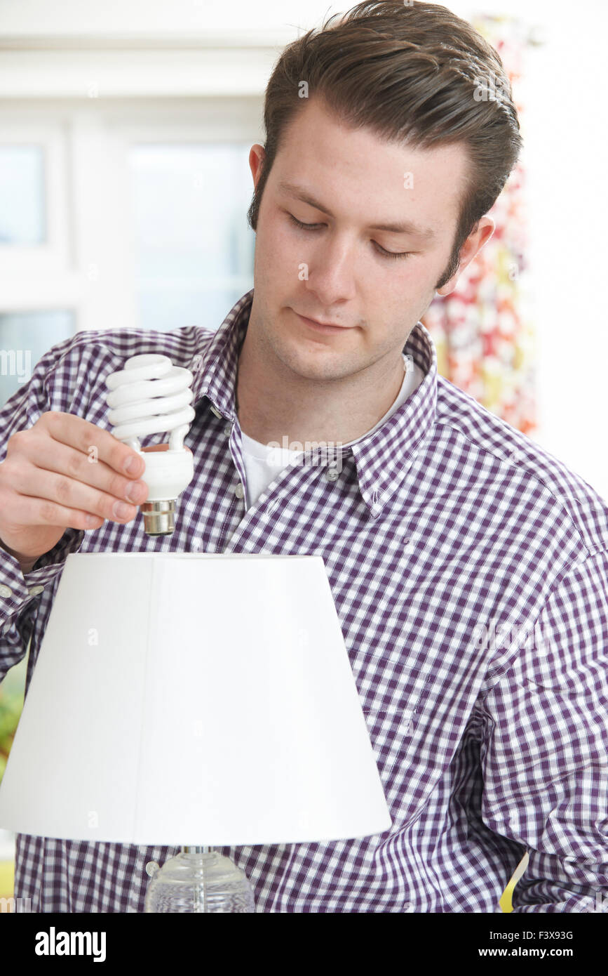 Man Putting Low Energy Lightbulb Into Lamp At Home Stock Photo Alamy
