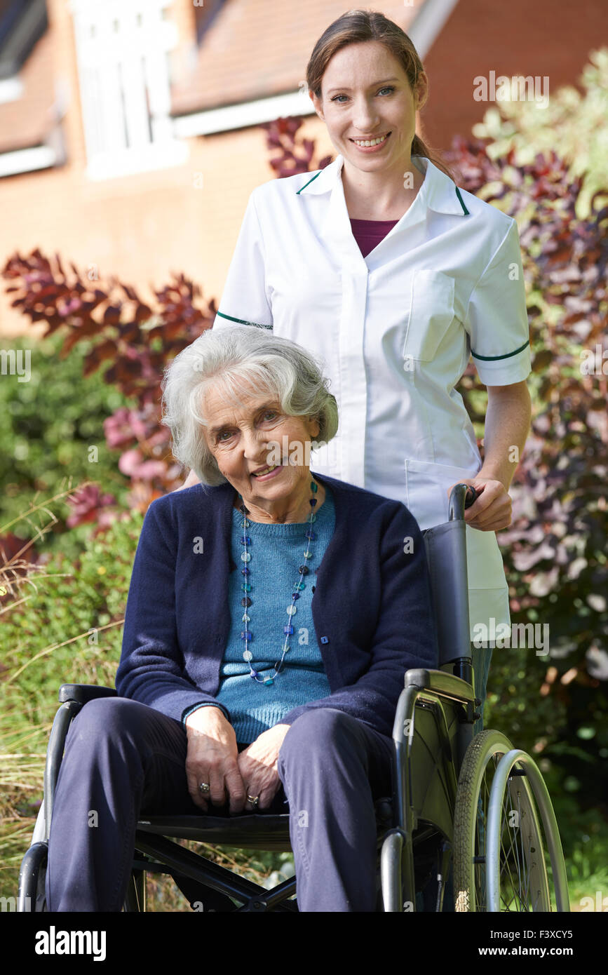Portrait Of Carer Pushing Senior Woman In Wheelchair Stock Photo