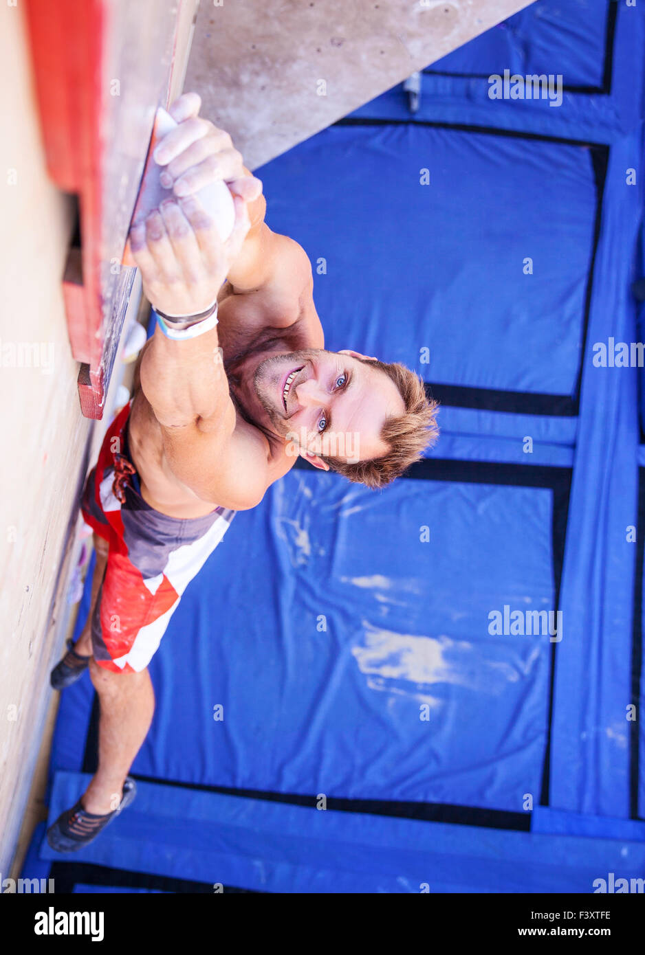 Rock climber participating in climbing competition, gripping top handhold Stock Photo