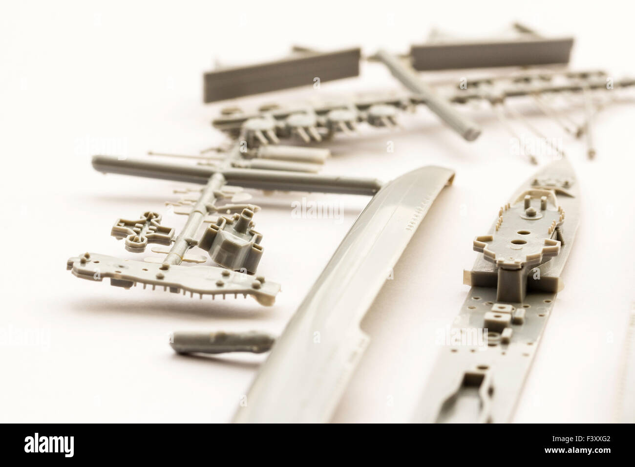 Plastic model kit. Airfix 1/600 scale model kit of second world war destroyer. Grey plastic parts connected to spur on white background, Close up. Stock Photo