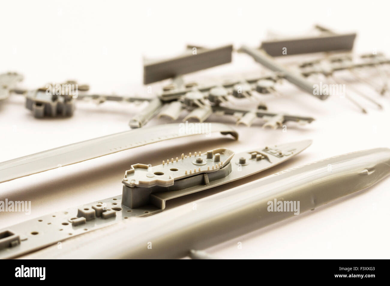 Plastic model kit. Airfix 1/600 scale model kit of second world war destroyer. Grey plastic parts connected to spur on white background, Close up. Stock Photo