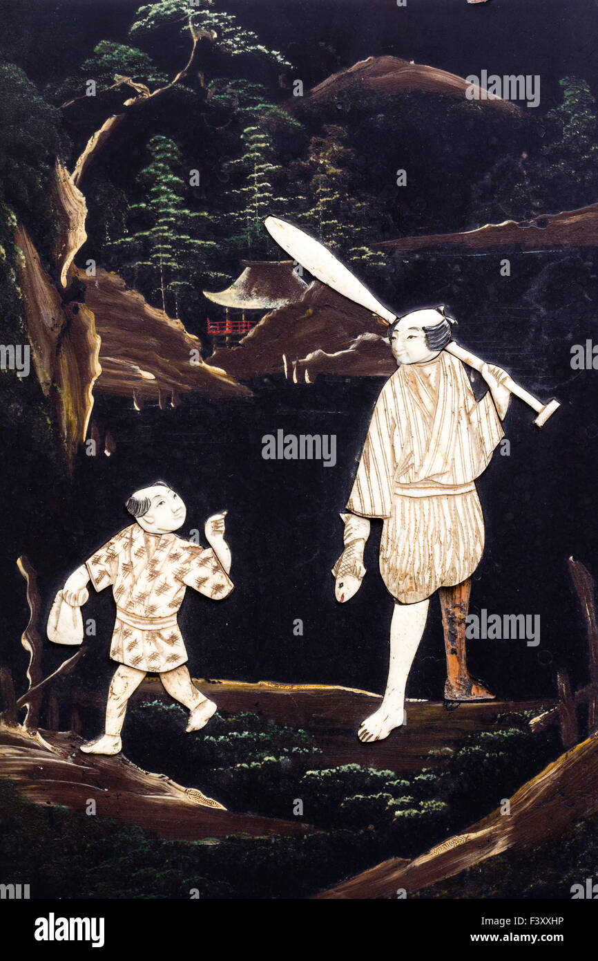 Japanese Shibayama bone and black lacquer panel, with inset mother of pearl figures of man and boy in rural Japan, background green trees and temple. Stock Photo