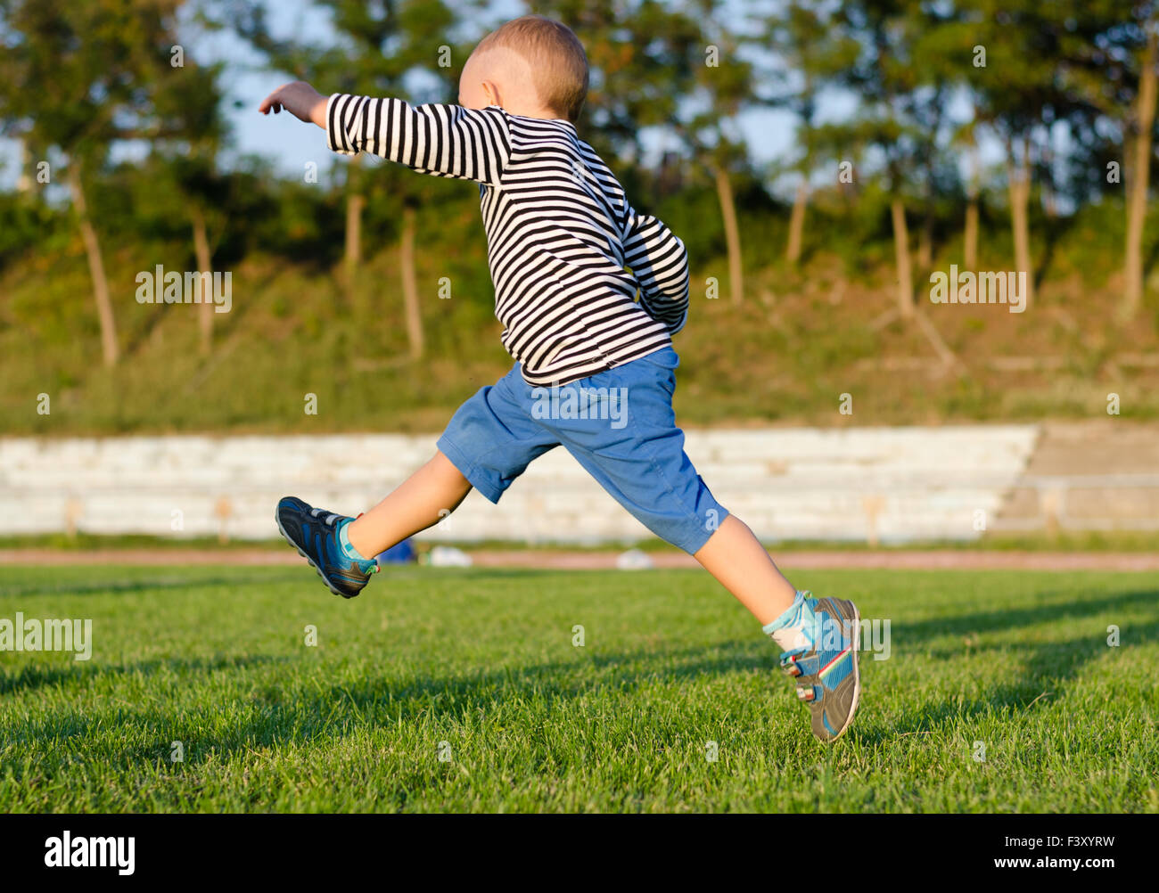 Little boy midair kicking a ball Stock Photo