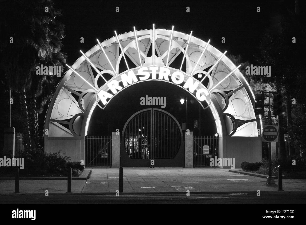 The lighted Metal archway entrance glows at night leading to the impressive Armstrong Park in the Treme area of New Orleans, LA Stock Photo