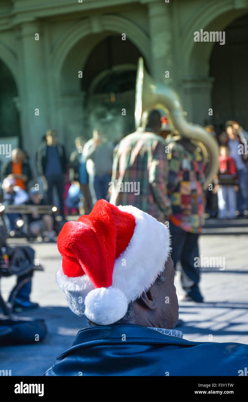 Rear view of man wearing Santa hat enjoying entertainment by street musicians, Jackson Square, French Quarter, New Orleans, LA Stock Photo