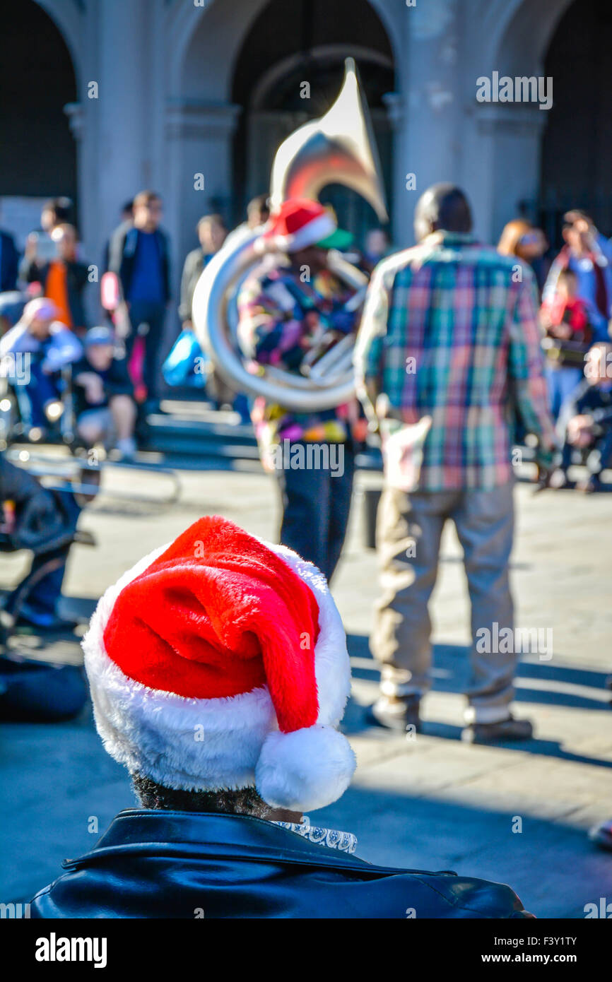 Rear view of man wearing Santa hat enjoying entertainment by street musicians, Jackson Square, French Quarter, New Orleans, LA Stock Photo
