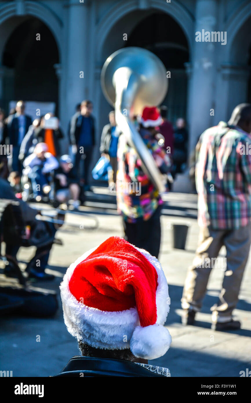 Rear view of man wearing Santa hat enjoying entertainment by street musicians, Jackson Square, French Quarter, New Orleans, LA Stock Photo
