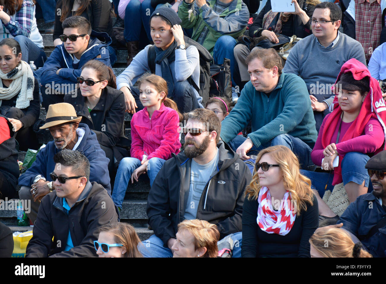 Multitude of diverse people in the USA sitting on bleachers reacting and watching an event Stock Photo