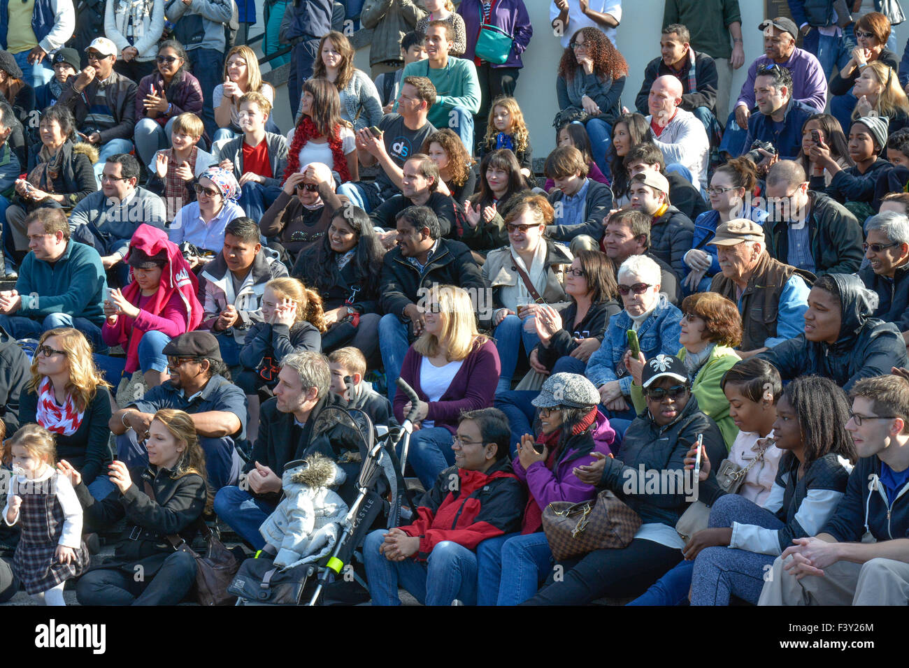 Multitude of diverse people in the USA sitting on bleachers reacting and watching an event Stock Photo