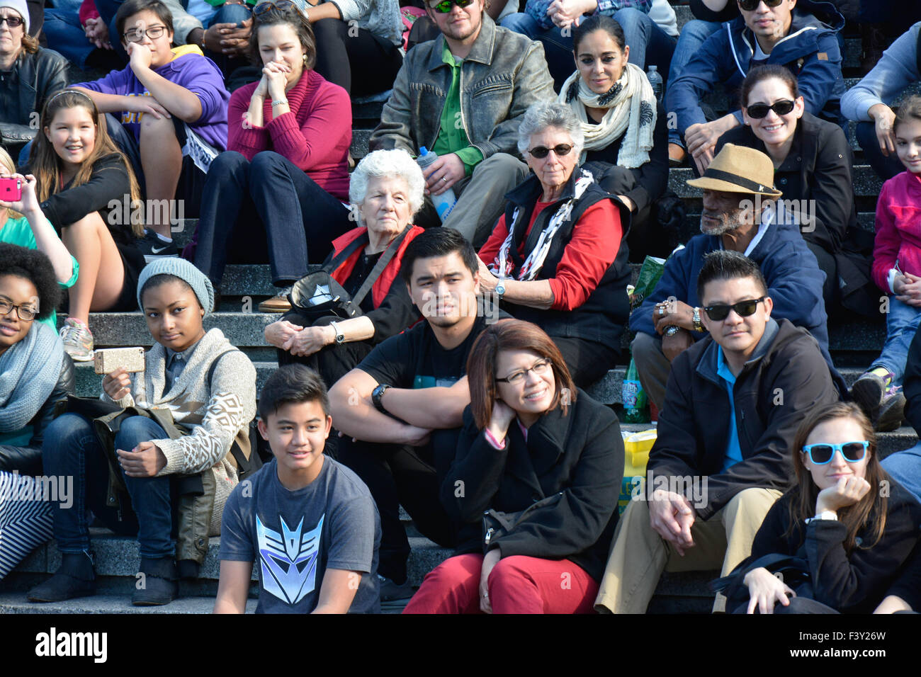 Large group of diverse people in the USA sitting on bleachers reacting and watching a street performance event Stock Photo