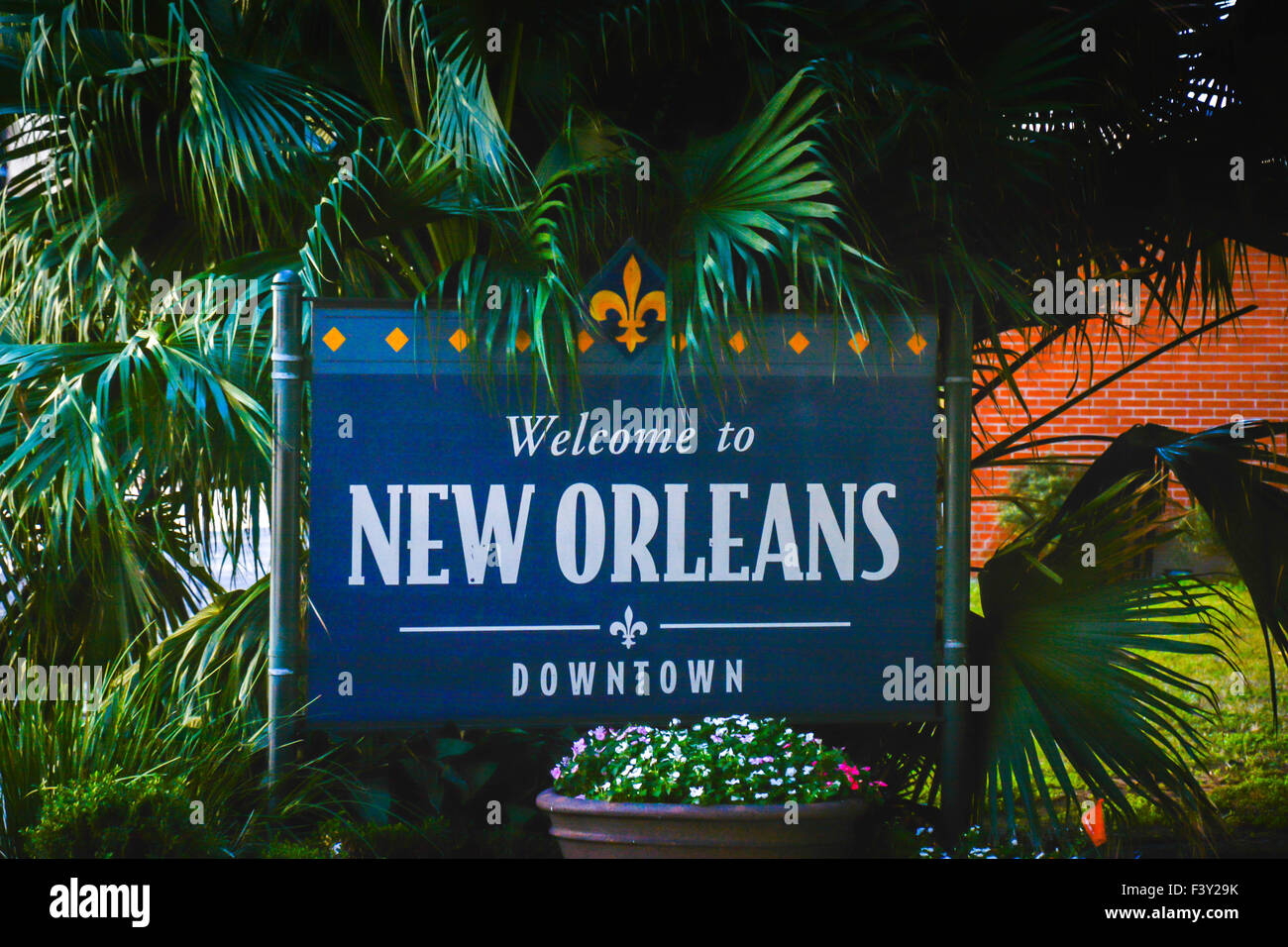 An attractive welcome sign with Fleur-de-lis for Downtown New Orleans, LA,  surrounded by lovely green palm trees and plants Stock Photo