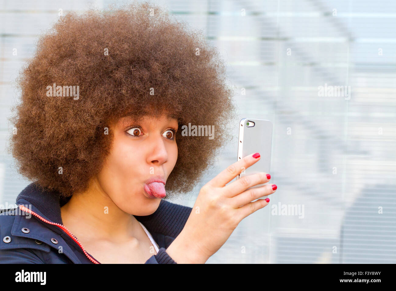 Young woman with afro hair cut makin a funny self portrait Stock Photo