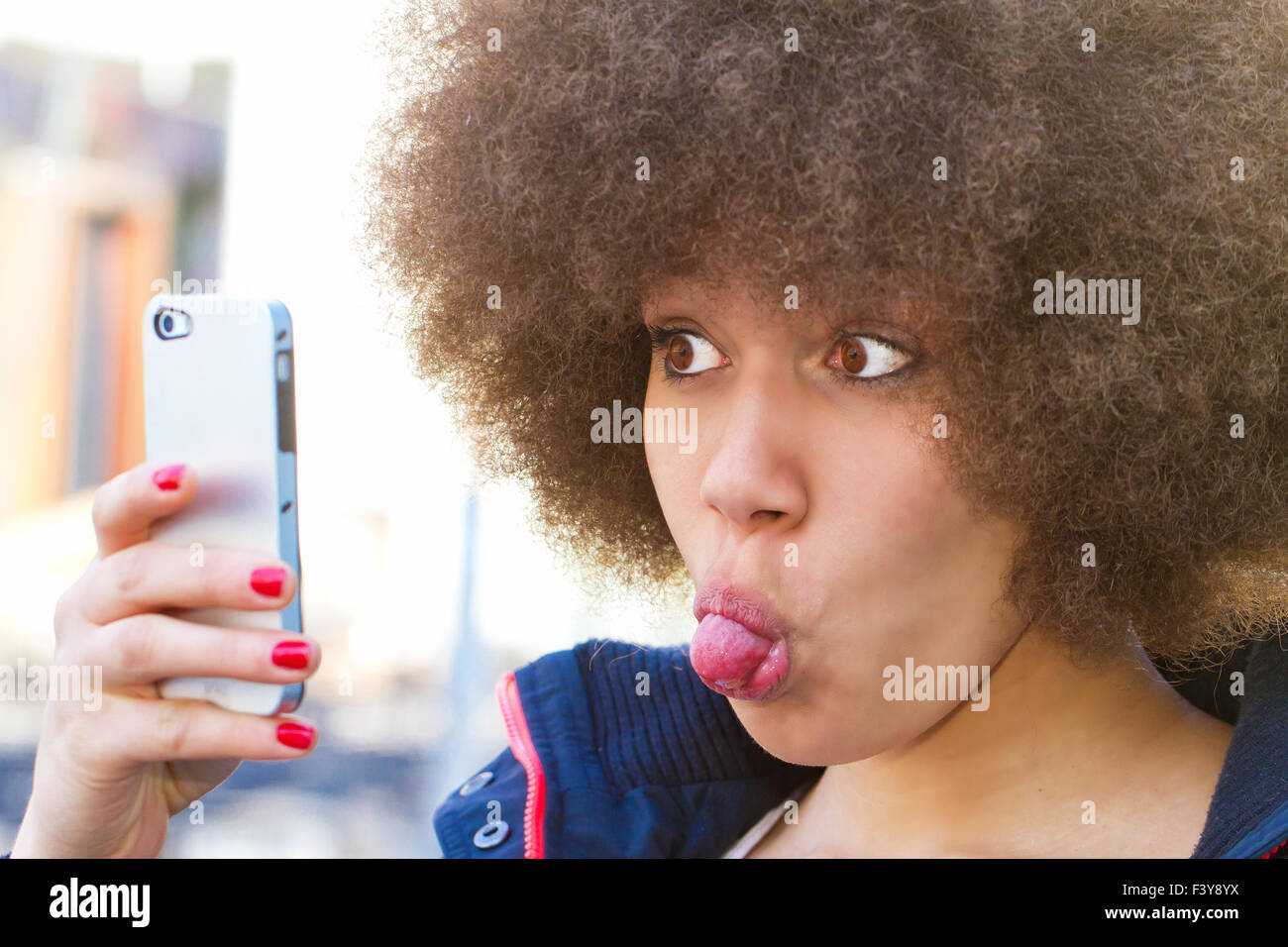 Young woman with afro hair cut makin a funny self portrait Stock Photo