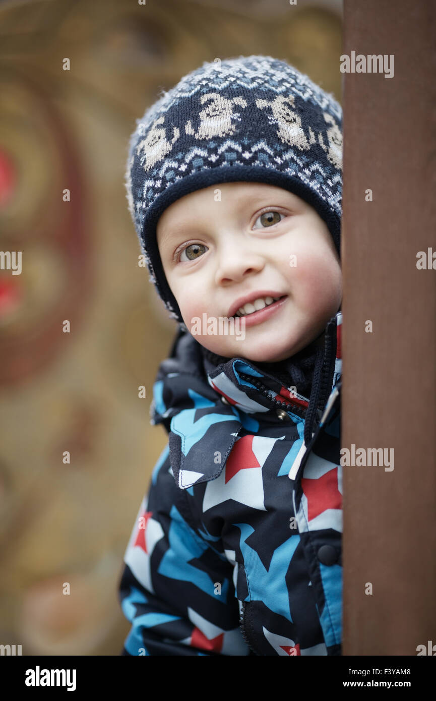 Cute little boy peering around a door Stock Photo
