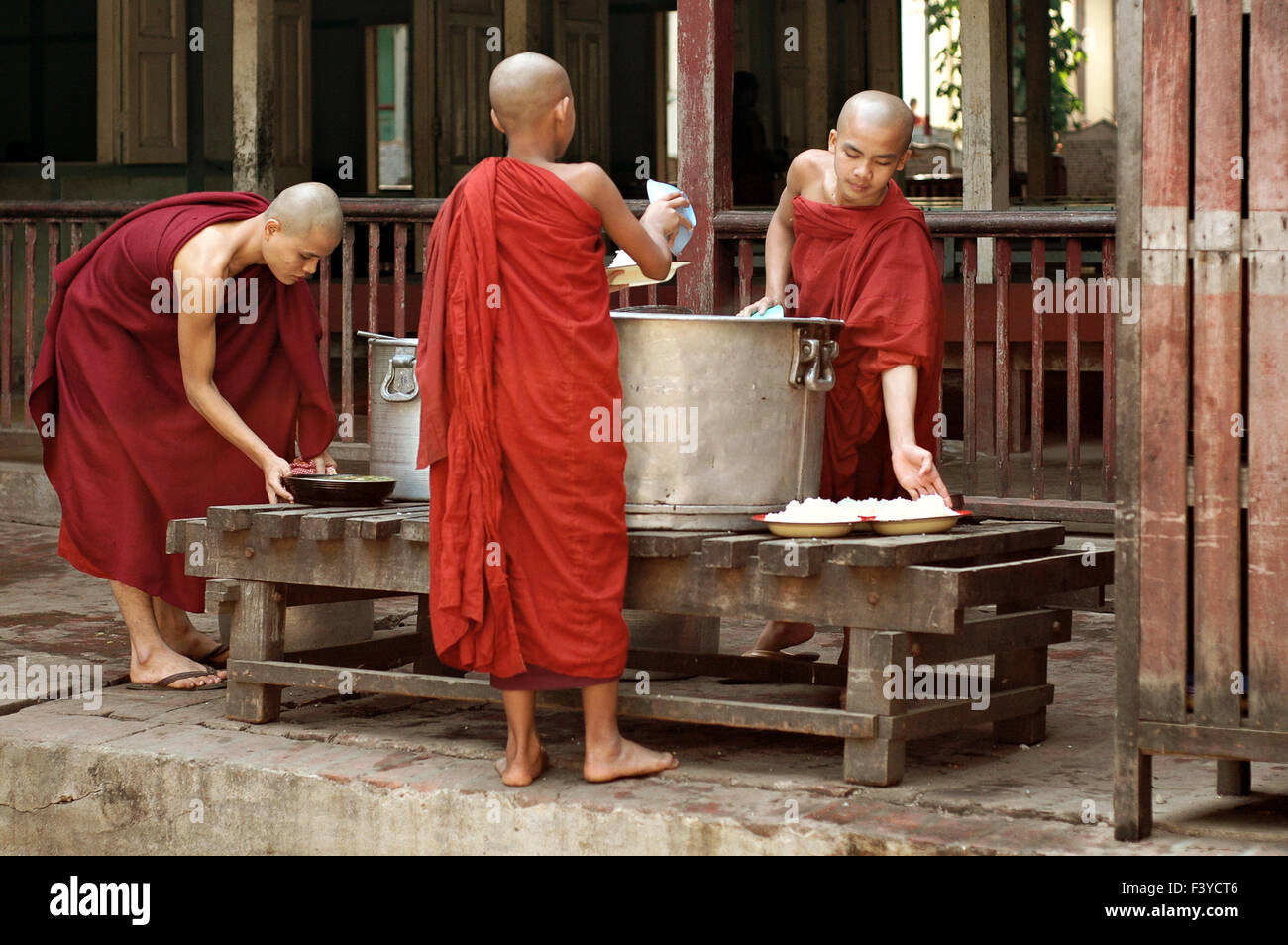 Three young burmese buddhist monks preparing meals for lunch at Maha Ganayon monastery, Amarapura, Mandalay Region, Myanmar Stock Photo